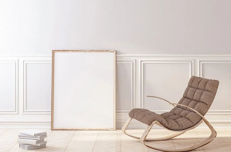 Silla mecedora tapizada junto a una pared blanca