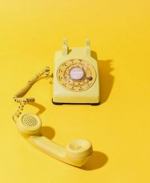 Teléfono amarillo de disco con el auricular descolgado