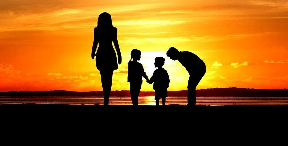 Siluetas de una familia frente al mar al atardecer