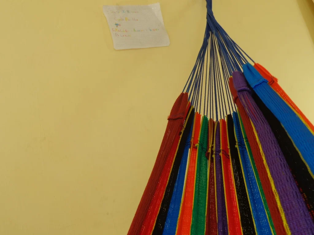 Hamaca de franjas de colores colgada junto a una pared amarilla