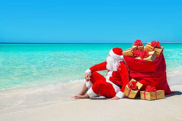 Imagen de Santa Claus sentado en la playa junto a regalos